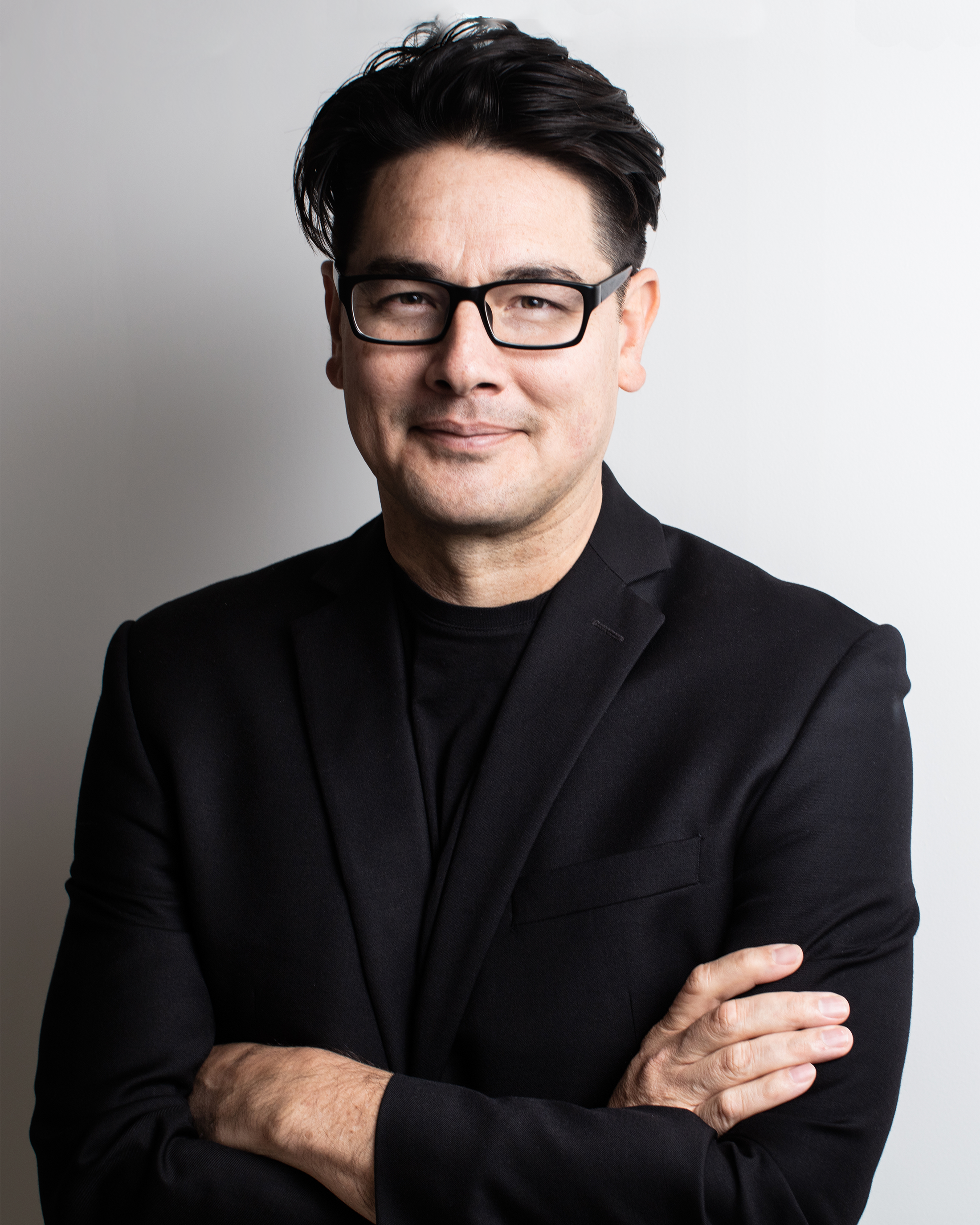 headshot of a man with short black hair, glasses, and suit
